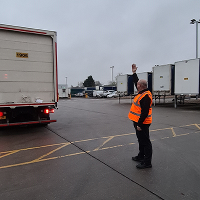 Reversing assistant in a high-visibility vest guiding a lorry